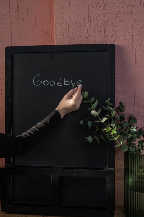 person writing goodbye on a chalkboard